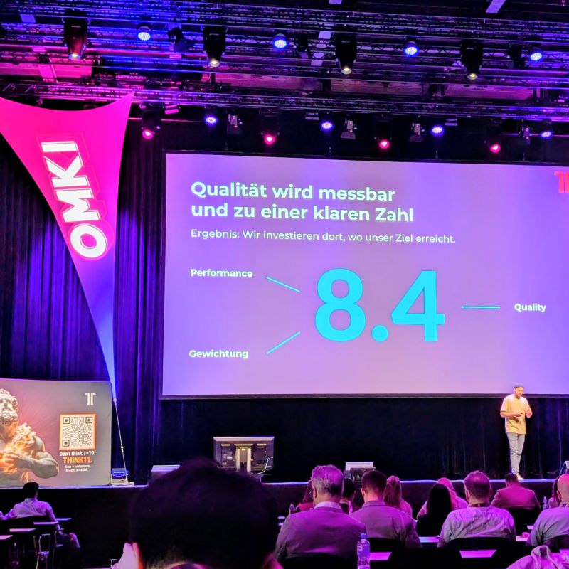 Bühnenmoment auf der OMKI 2026 mit einer Performance-Folie und Publikum im Vordergrund